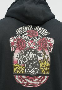 Mustapaita, jossa on värikäs graafinen suunnittelu koirasta auringonkukilla, ruusilla ja koristeelementeillä, painettuna selkäpuolelle.