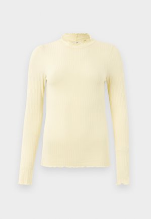 Langermet, ribbestrikket topp i myk pastellgul med høy volangkrage og bølget kant; laget av elastisk stoff for komfort.