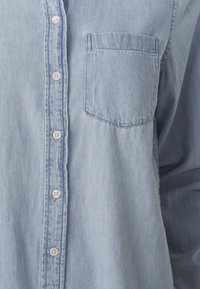 Lichtblauwe denim overhemd met een knoopsluiting aan de voorkant, een enkele borstzak en lange mouwen met een ontspannen pasvorm.