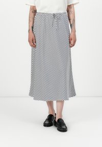 Stripete midi-skjørt i hvit og marineblå, med snøring i livet og lett stoff. Kombinert med svarte loafers.