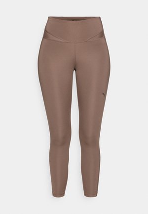 Legginguri atletice maro, realizate dintr-un material neted și elastic, cu un talie înaltă. Au un logo mic negru pe partea inferioară a piciorului stâng.