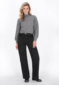 Grå, ribbet striktrøje med høj hals og puffede ærmer, parret med højhalsede sorte wide-leg jeans og sorte ankelstøvler.