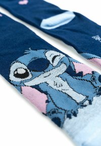 Calzini blu con un personaggio dei cartoni animati dai grandi occhi e un ampio sorriso, su uno sfondo blu scuro con accenti rosa.