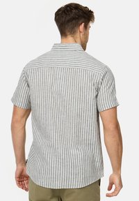 Camisa de manga corta en tejido gris claro con rayas verticales blancas, que presenta un cuello, una costura en el yugo y un dobladillo redondeado.