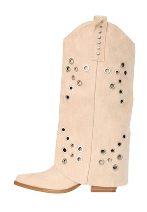 Bota vaquera de ante beige con múltiples ojales y tachuelas de metal plateado, punta puntiaguda y tacón bajo de madera.