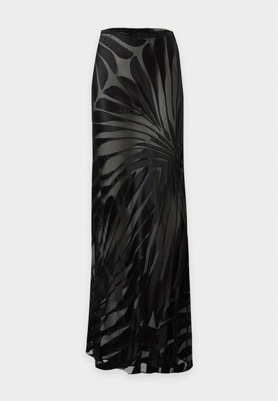 Longue jupe noire avec un voile transparent orné d'un motif abstrait de feuilles tourbillonnantes, présentée sur un fond clair.