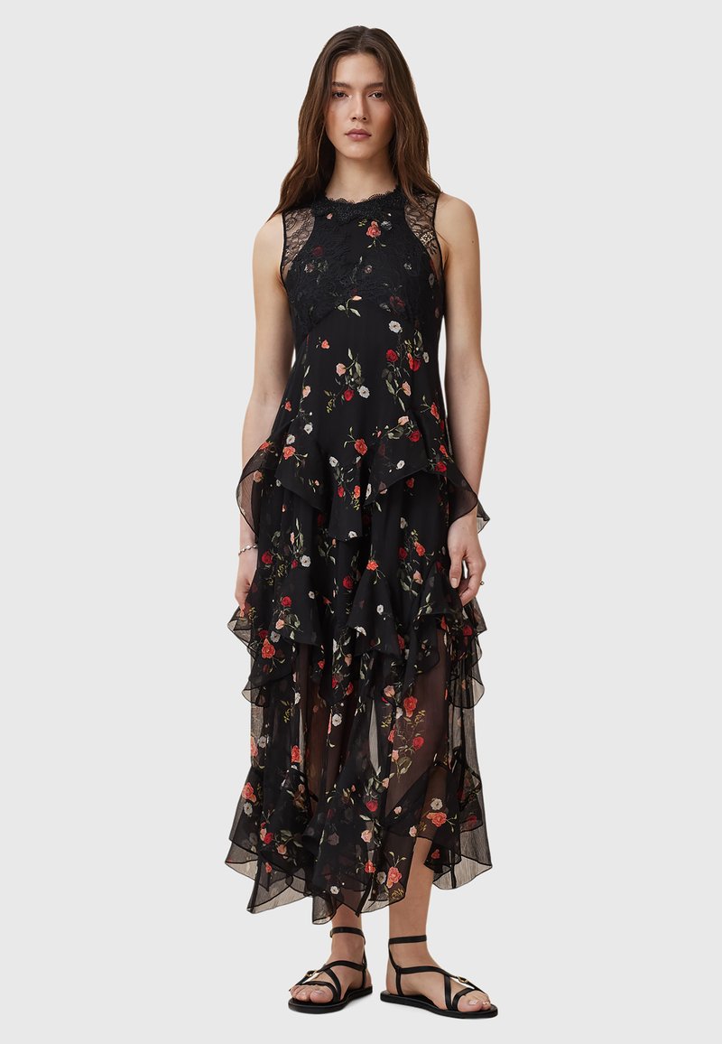 Black floral maxi dress with layered ruffles, featuring a lace neckline and accents of red and white flowers. Worn with black sandals.