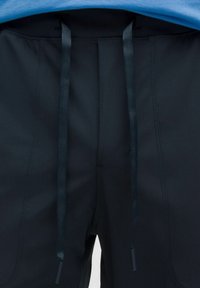 Pantaloni sportivi neri realizzati in tessuto liscio e elasticizzato. Dotati di una vita con coulisse e cuciture laterali per un look aderente.