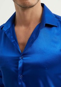 Chemise en satin bleu brillant avec un col pointu, fermeture par boutons et texture lisse, mettant en valeur une couleur profonde et riche ainsi qu'une coupe près du corps.
