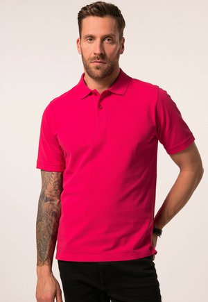 Kurzarm-Polohemd in leuchtendem Pink, aus Baumwolle gefertigt, mit einem kragenartigen Hals und einer Knopfleiste mit drei Knöpfen, kombiniert mit schwarzen Hosen.