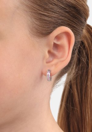 Orecchino a cerchio in argento con gemme rosa, superficie liscia e design leggermente curvato. Attaccato a una vista parziale dell'orecchio.
