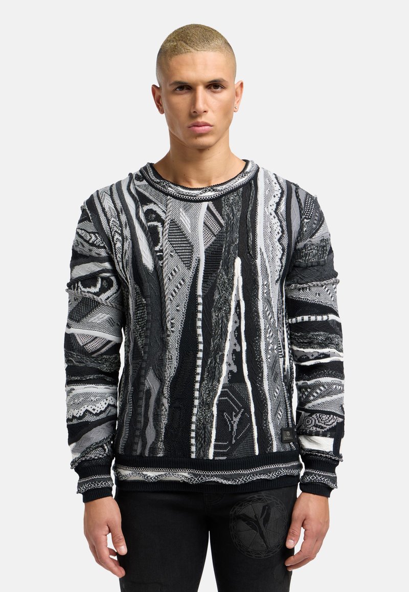 Pull en tricot noir et gris avec des motifs et textures complexes, doté de manches longues et d'un col rond. Les accents incluent une étiquette sur l'ourlet.