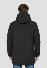 Veste noire à capuche avec une texture lisse et mate et une coupe longue. Les détails sont minimalistes, sans éléments visibles ni accents au dos.