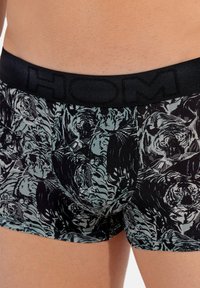 Schwarze Boxershorts mit einem Tiger-Muster in Grautönen. Der Bund ist elastisch, mit dem in Schwarz eingeprägten Markennamen "HOM".