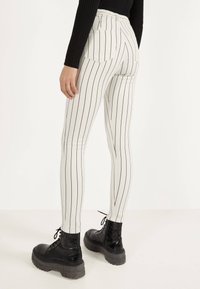 Vita randiga leggings med hög midja och bakfickor, i kombination med svarta snörade kängor med kraftig sula och skinninlägg.