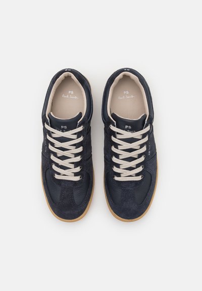 Mørkeblå joggesko med en kombinasjon av semsket skinn og lær, kremfargede snørebånd, rund tå og såle av gummigummi.