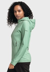 Mintgrüne Kapuzenjacke mit gerippter Textur, vorderer Reißverschlusstaschen und Logo-Detail an den Ärmeln. Leichtes und figurbetontes Design.