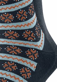 Schwarze Stricksocke mit hellblauen und rostfarbenen Mustern. Verziert mit Schneeflockenmotiven und gewellten Streifen entlang der Stoffstruktur.