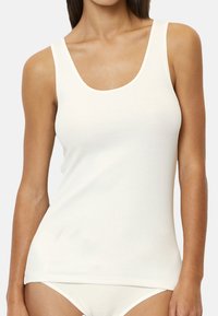 White cotton tank top with a scoop neckline and slim fit. Features smooth texture and lightweight fabric. Ideal for layering or casual wear.