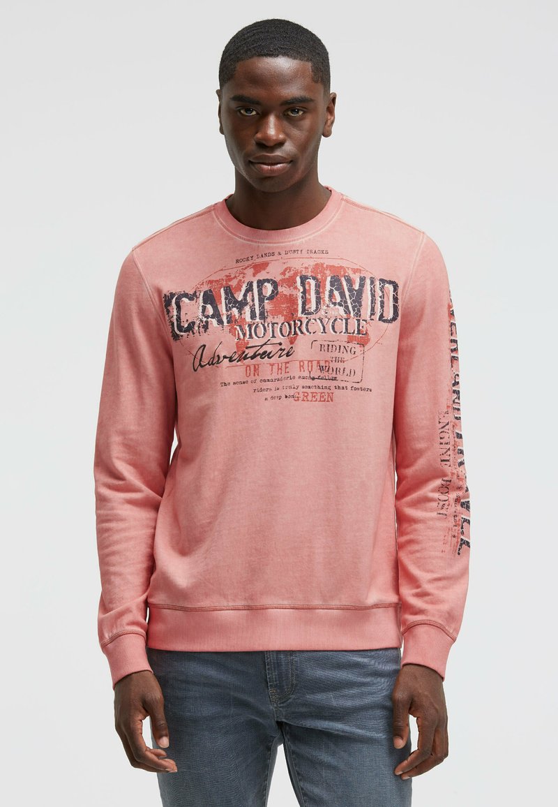 Rosa Sweatshirt mit langen Ärmeln, rundem Halsausschnitt und grafischen Motiven auf der Vorderseite. Der Text beinhaltet "CAMP DAVID" und "MOTORCYCLE." Weicher, lässiger Stoff.