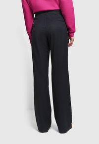 Spodnie szerokie w ciemnoniebieskim materiale z żebrowaną fakturą, z wysokim stanem, boczną kieszenią i dopasowanym krojem z tyłu.