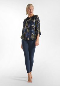 Top multicolore caratterizzato da una vestibilità ampia, maniche a batwing e un mix di motivi verdi, blu e viola. Abbinato a leggings blu navy.