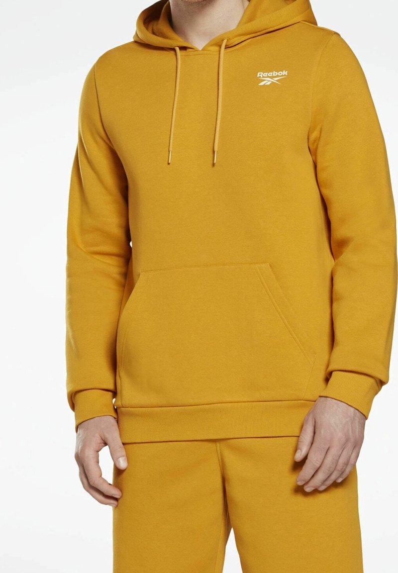 Sweat à capuche jaune en tissu doux, avec une poche kangourou et des poignets côtelés. Logo affiché sur la poitrine en blanc.