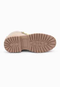 Suela de bota en goma de color rosa claro con profundas ranuras, que presenta una sección plana y pequeños patrones de estrellas para proporcionar tracción y durabilidad.