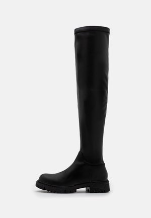 Black knee-high boot with rounded toe and chunky treaded sole, smooth finish, and pull-on style against plain light background.