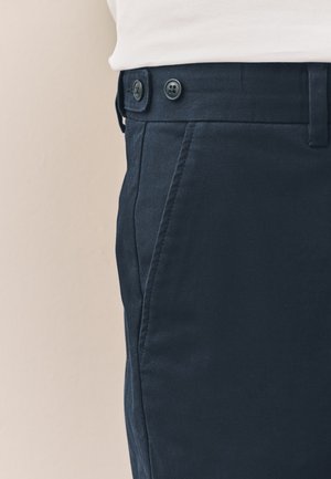 Marineblaue Hose aus glattem Stoff, mit zwei Seitentaschen und Zweiknopfverschluss, mit tailliertem Schnitt und sauberen Nähten.