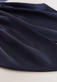 Marineblaue Satinstoff, glatte Textur, in weichen Falten drapiert, mit einem leichten Glanz, der ein fließendes und geschmeidiges Design zeigt.