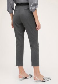Pantaloni a righe grigie con vestibilità sartoriale, lunghezza alla caviglia e due tasche posteriori. Abbinati a scarpe argento con dettaglio a fiocco.