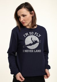 Sudadera azul marino de mezcla de algodón con mangas largas, presenta una estampado gráfico de una figura volando y el texto: "SOY TAN FLY QUE NUNCA Aterrizo."