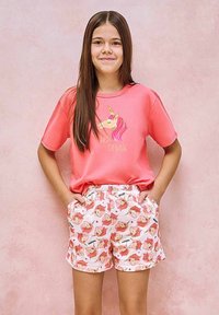 Różowa koszulka z grafiką jednorożca z okrągłym dekoltem, zestawiona z kolorowymi szortami z wzorem jednorożców w różu i kremie. Miękki materiał.