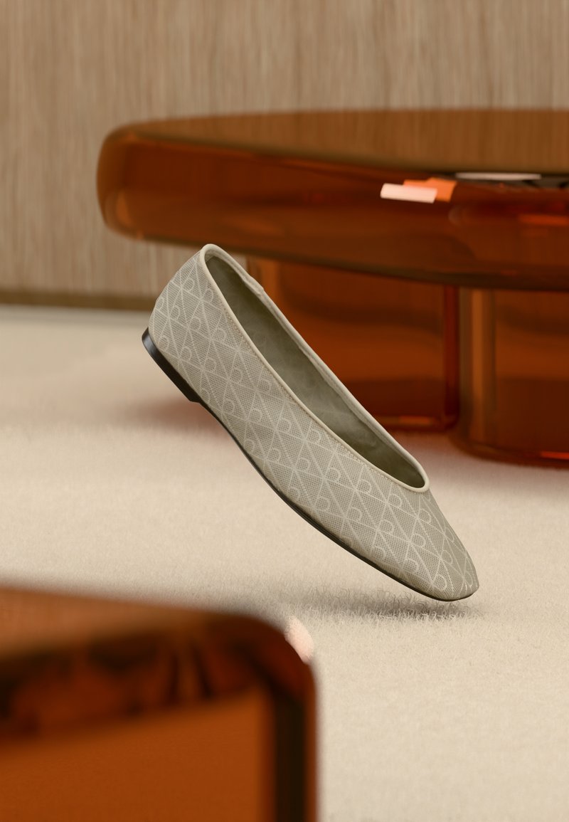 Ballerine beige à motif géométrique flottant au-dessus d'un tapis clair dans une pièce moderne avec des meubles aux tons ambrés.