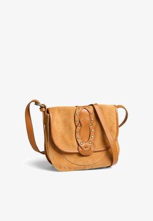 Petit sac bandoulière en daim beige avec sangle en cuir et rabat, orné d'une décoration ovale en cuir avec des clous métalliques sur le devant.