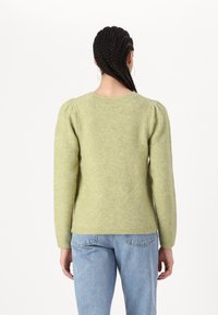 Grønn strikket genser med puffede ermer og ribbede mansjetter. Myk tekstur, rund hals, figursydd silhuett. Brukt sammen med lyseblå jeans.