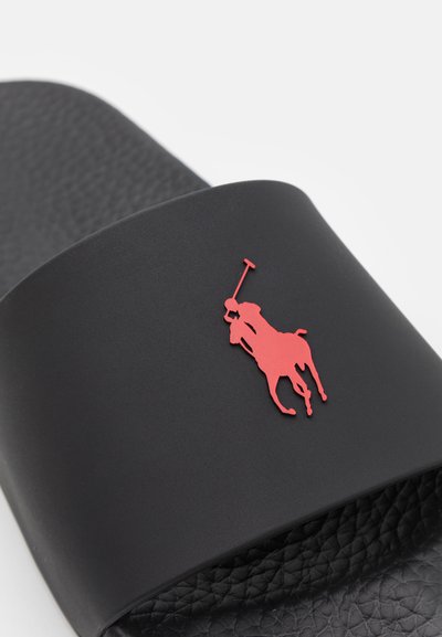 Musta liukusandaali, jossa on teksturoitu musta sisäpinta ja etustrapissa selkeä punainen polo-logo. Valmistettu kestävästä materiaalista.