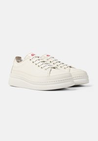 Sneakers bianchi in pelle, modello low-top con punta rotonda, chiusura con lacci, colletto imbottito e suola in gomma testurizzata. Presentano accenti del logo rosso sulla linguetta.