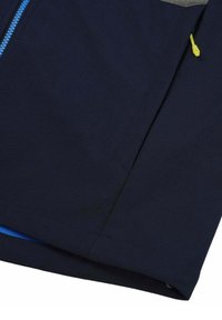 Navy blue soft-shell jacket with a gray top section, featuring a blue zipper and a yellow pull tab, designed with a smooth texture and modern cut.