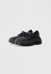 Chaussures noires avec une tige en cuir texturé, semelle en caoutchouc noir épaisse et détails de couture orange. Dotées d'un design à lacets et d'une sangle réglable.