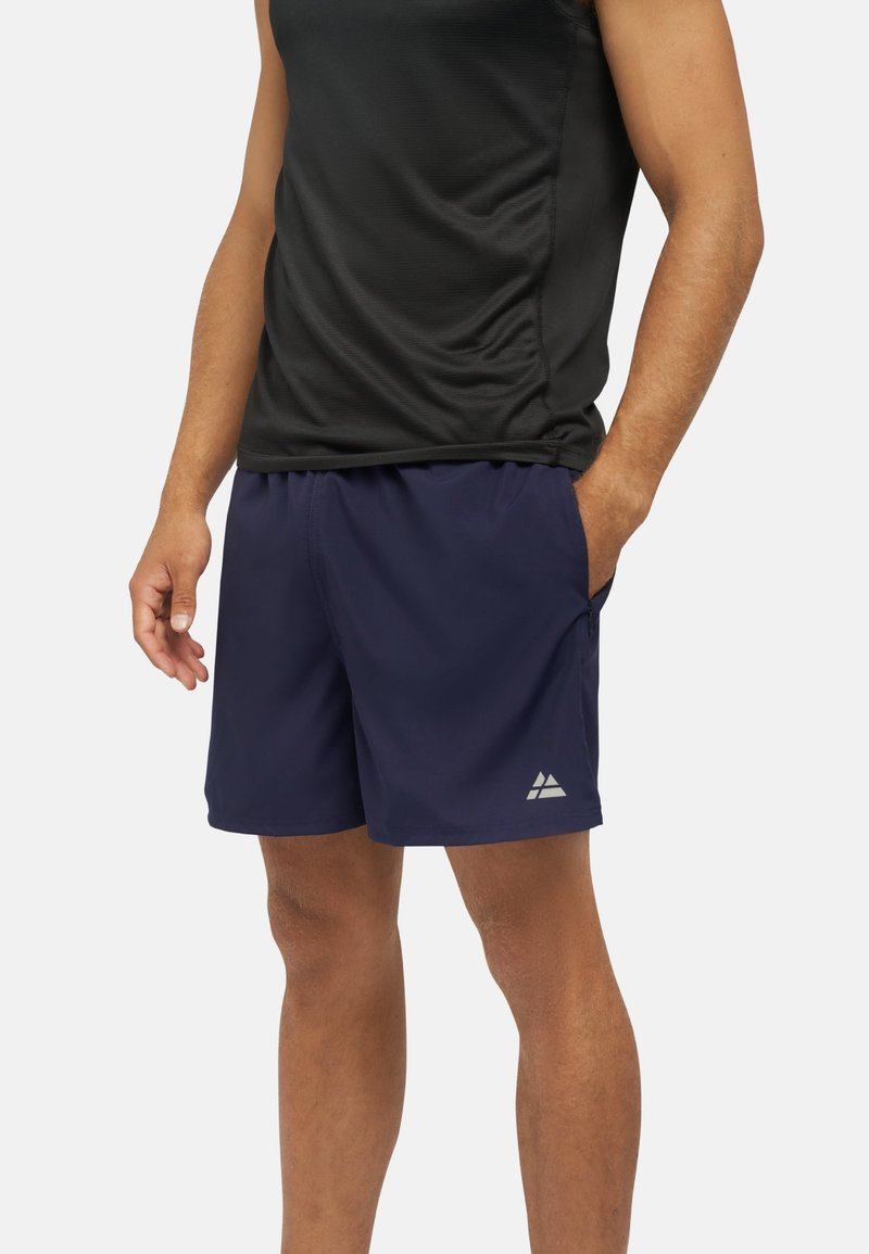 Pantaloni sportivi blu navy con vita elastica, tasche laterali e un logo riflettente. Realizzati in tessuto leggero e traspirante.