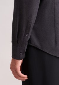 Camicia button-up grigia scura con tessuto testurizzato, maniche lunghe con polsini abbottonati e orlo arrotondato.