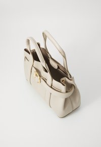 Sac à main en cuir beige avec poignées doubles, détails en matériel doré, forme structurée et texture lisse. Ouvert sur le dessus avec des compartiments intérieurs.