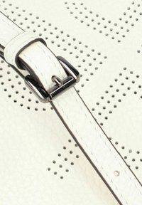 Cinghia di borsa in pelle bianca con design perforato, dotata di chiusura a fibbia metallica e superficie liscia.