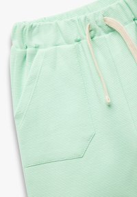 Lys grønne ribbede stofshorts med elastisk talje, frontlomme og beige snor.