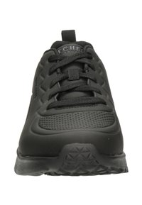 Czarny sportowy but z teksturowaną cholewką, sznurowanym zapięciem i wyściełaną podeszwą. Cechy obejmują perforacje oraz podeszwę z trójkątnym wzorem.