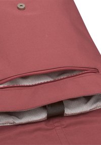 Piros szövet tasak, cipzárral záródó nyílással, csíkos bélésbelsejével és a frontrészen elhelyezett kör alakú fém patokkal.