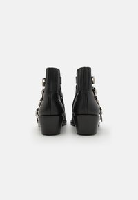 Botine negre din piele cu spate texturat, accente din metal argintiu și toc masiv. Designul include panouri laterale elastice.