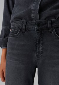Jeans in denim grigio scuro con un design classico, dotati di chiusura a bottone, passanti per cintura e tasche. Tessuto morbido con dettagli di leggera scoloritura.